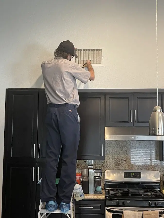 Technician inspecting an air vent during HVAC service in Asheville